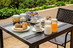 Une table dressée avec des aliments pour le petit-déjeuner, notamment des croissants, du pain, du lait, du café et une boisson aux fruits.