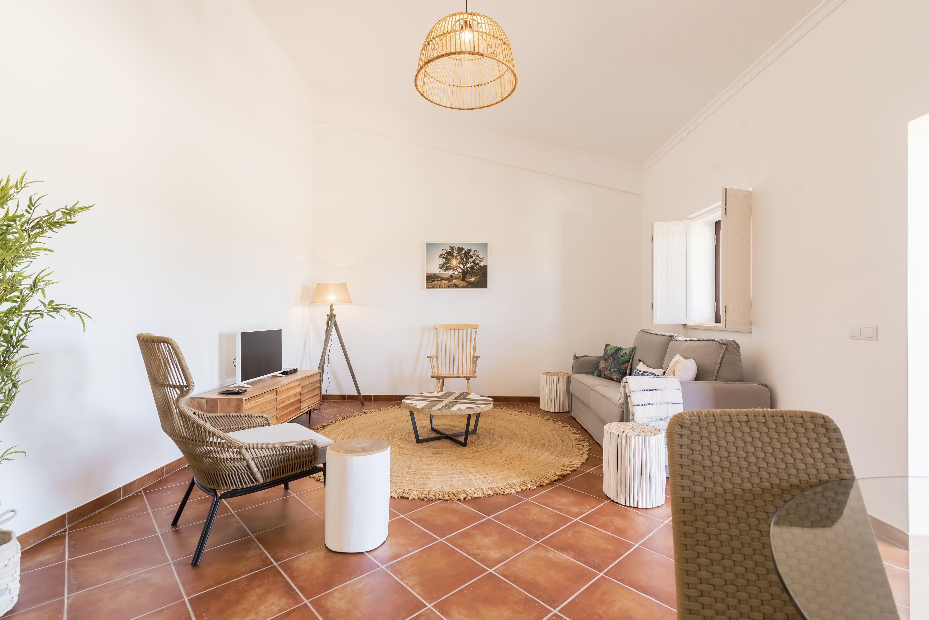 Una sala de estar con alfombra redonda, un sofá, una silla, un televisor y una lámpara.