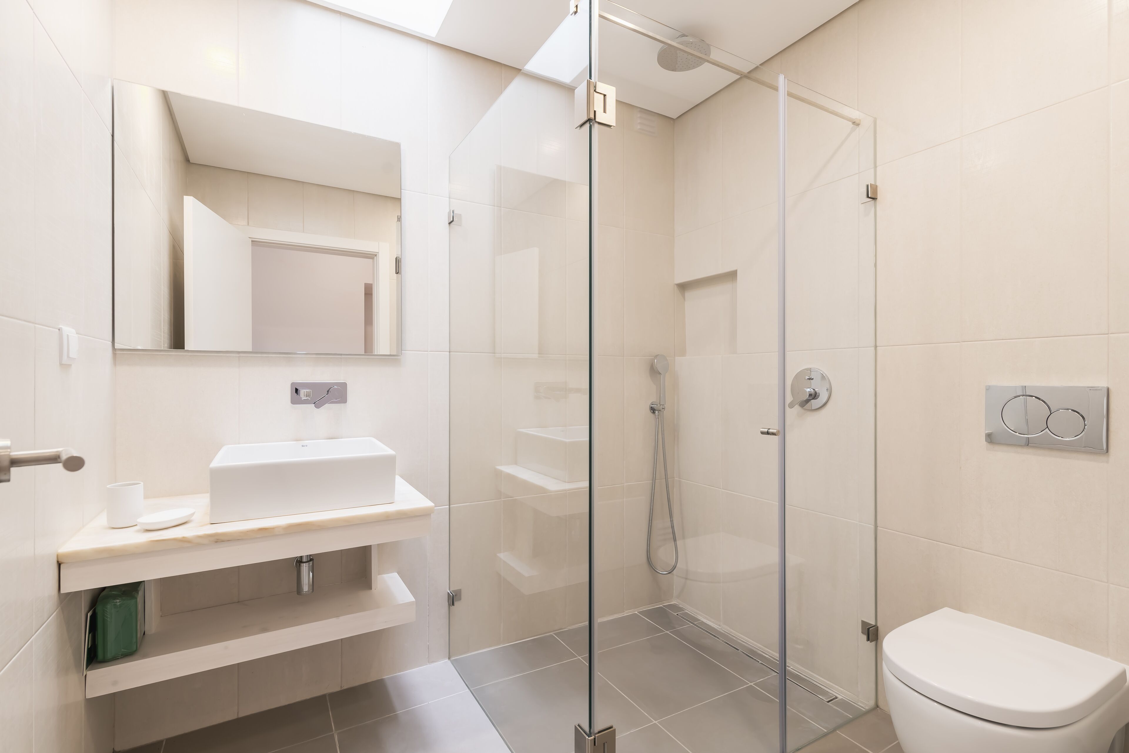 Une salle de bain moderne avec une douche à parois de verre, un lavabo blanc et des toilettes.