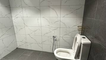 Un baño moderno con inodoro, ducha y azulejos de mármol.