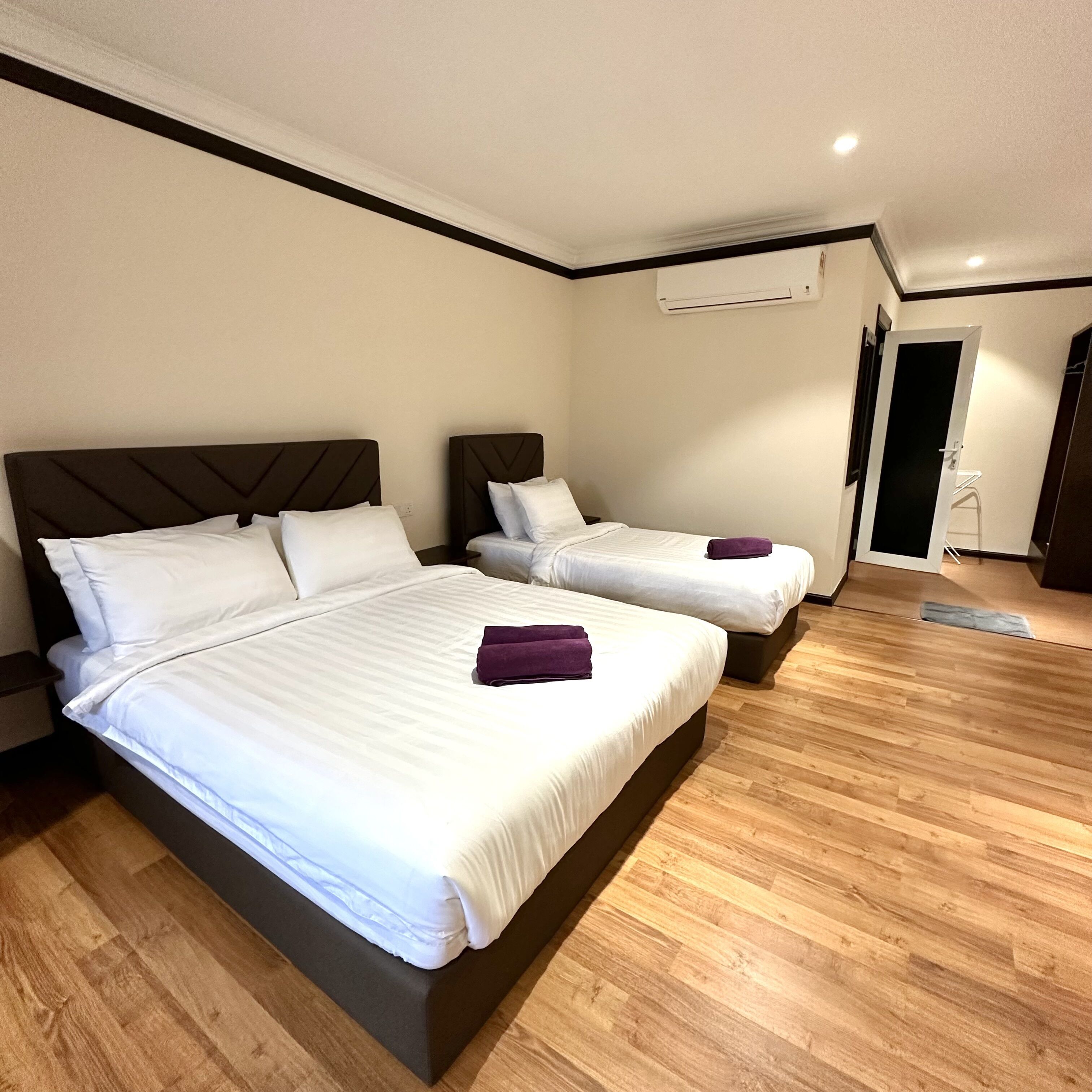 Camera d'albergo con due letti, pavimento in legno e condizionatore d'aria a parete.
