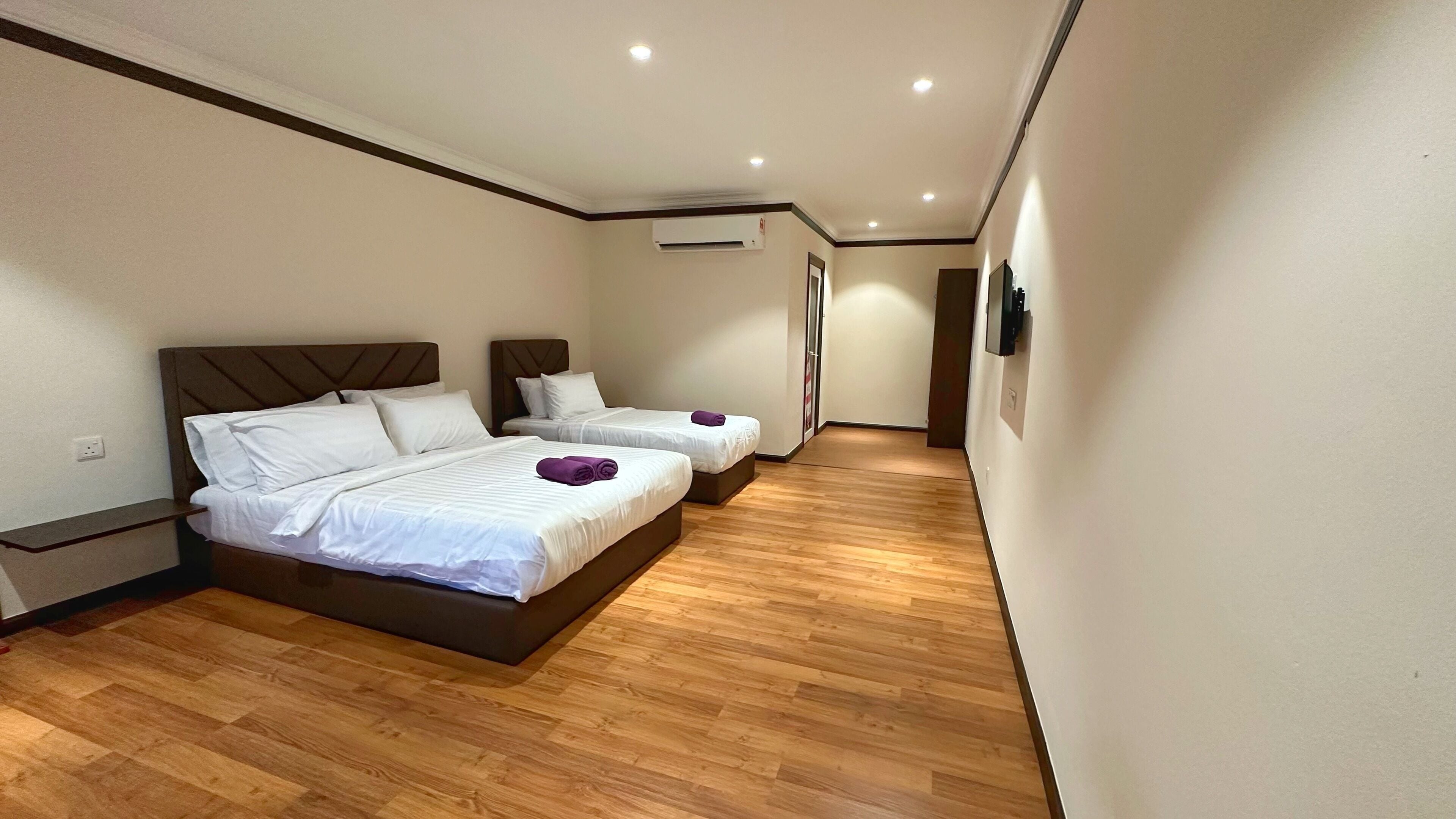 A hotel room with two beds, wooden flooring, and a modern design.