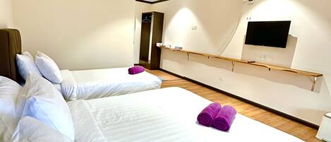 A hotel room with two beds, a TV mounted on the wall, and a wardrobe.
