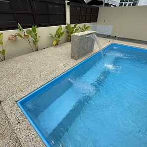 Une piscine rectangulaire avec un bord bleu, entourée d’un sol recouvert de petits galets.