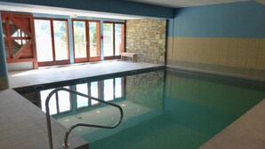 Ein Innenpool mit Steinwand und einer Holzbank.
