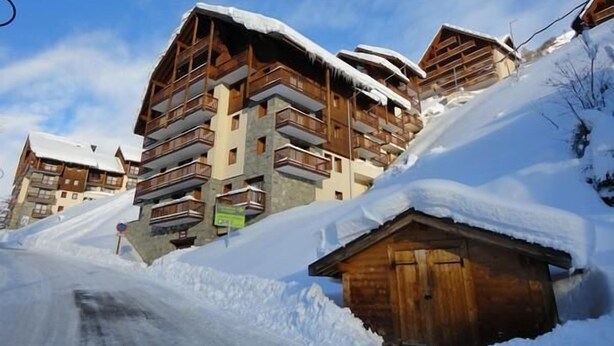 Ein mehrstöckiges Holzgebäude mit Balkonen, umgeben von Schnee.