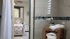 Ein Badezimmer mit Dusche, einem Holzboden mit Handtüchern, einem Bett und einem Waschtisch.