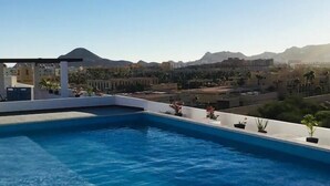 A rooftop swimming pool with a view of mountains and a cityscape. - Condos TE22 (Cabo San Lucas)