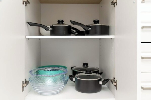 A kitchen cabinet with two shelves, each holding kitchenware.