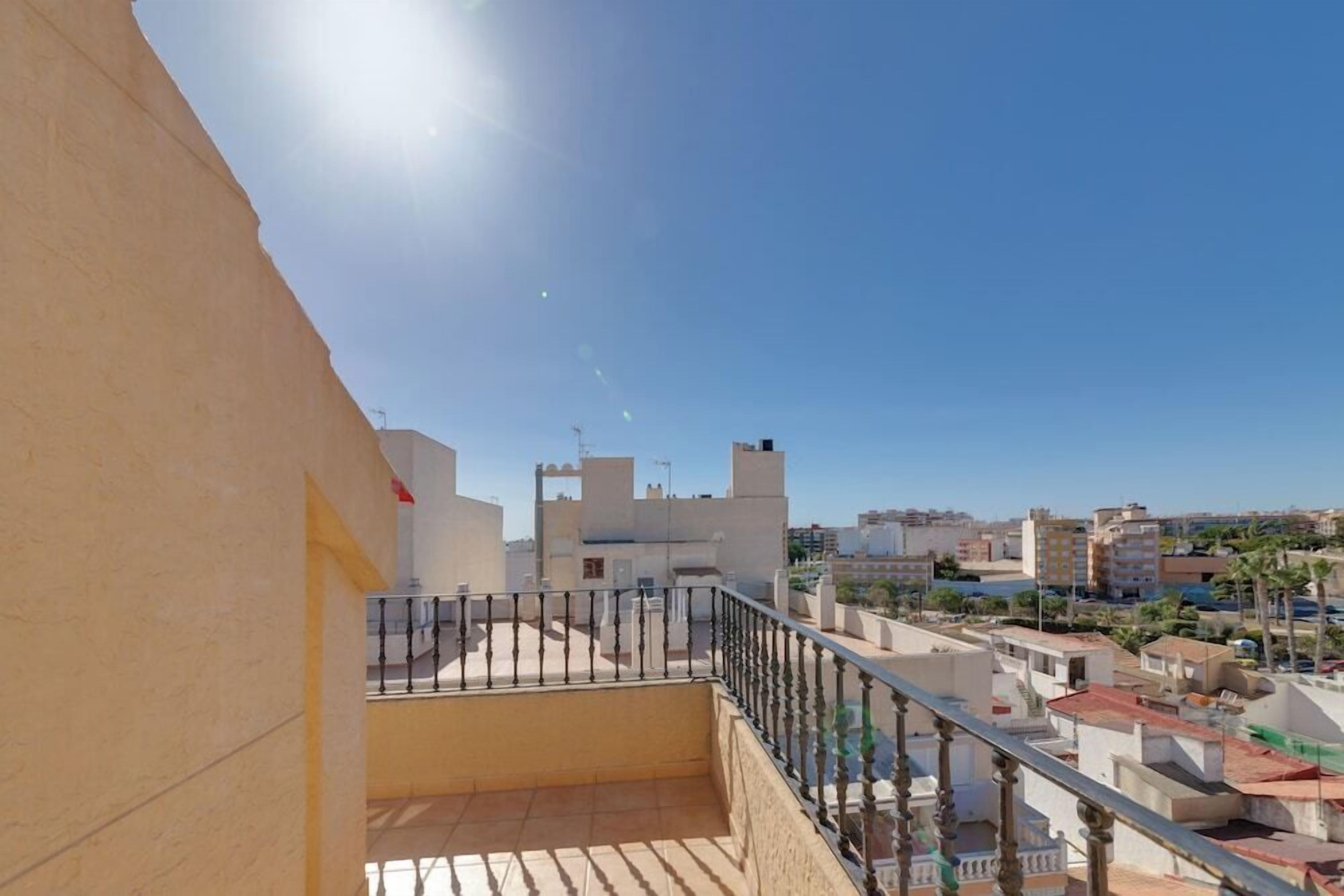 A balcony with a metal railing overlooking a cityscape.