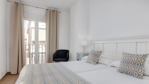A hotel room with a large bed, a chair, a nightstand, and a window with curtains. - Madrid Hotel (Torrevieja)
