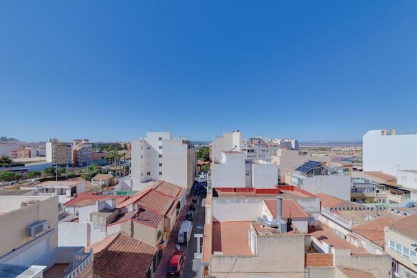 A cityscape with a mix of modern and traditional buildings, a clear blue sky, and a street with vehicles. - Madrid Hotel (Torrevieja)