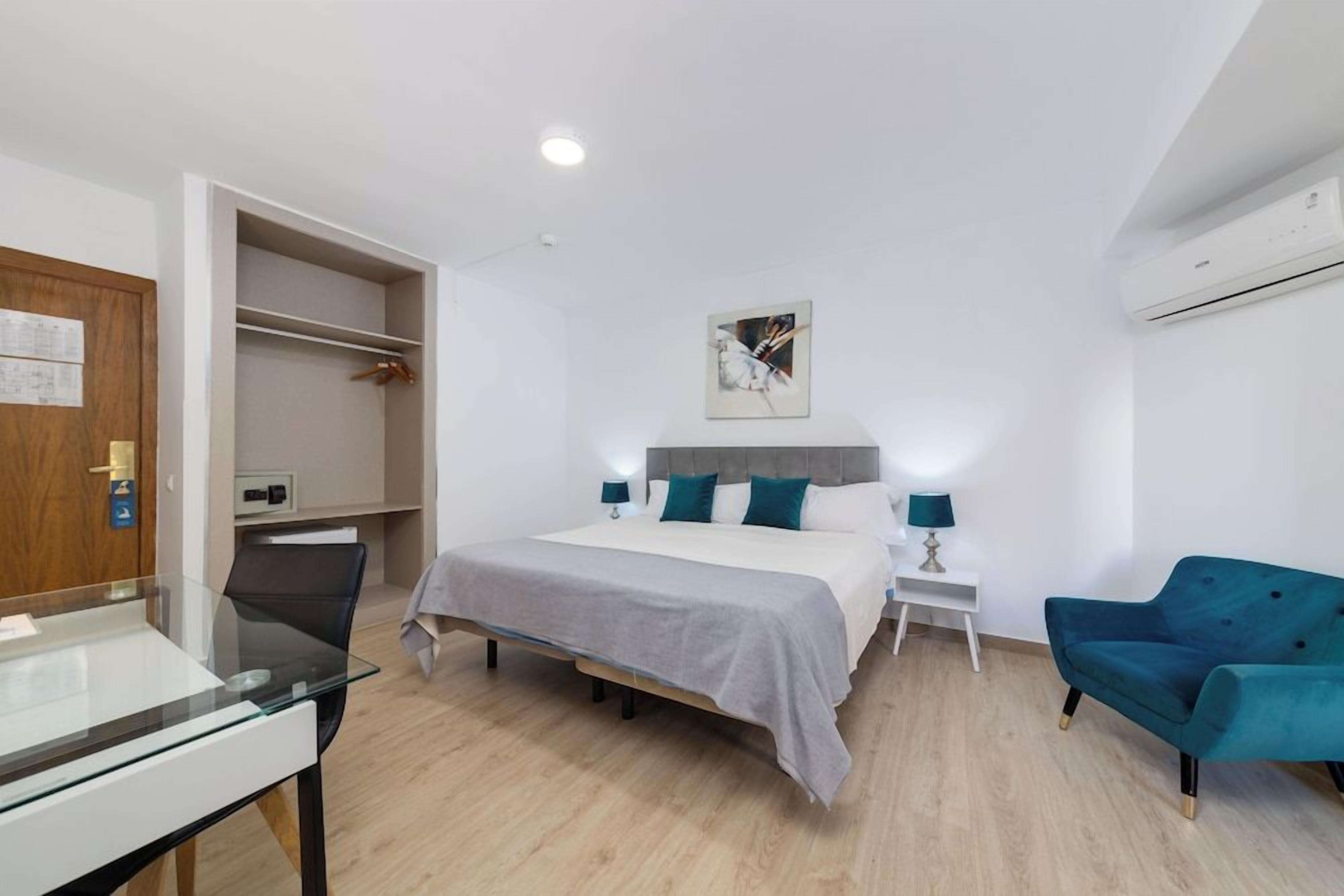 Een moderne slaapkamer met een bed, nachtkastjes, een bureau en een stoel.