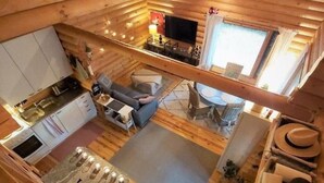 L’intérieur d’une cabane comprend une cuisine, un coin repas et un salon, avec des murs en bois et un lit en mezzanine.