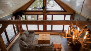 A cozy cabin interior with a plaid sofa, wooden coffee table, and a chandelier. - Mercer, WI Beautiful Flambeau Flowage Cabin (Butternut)