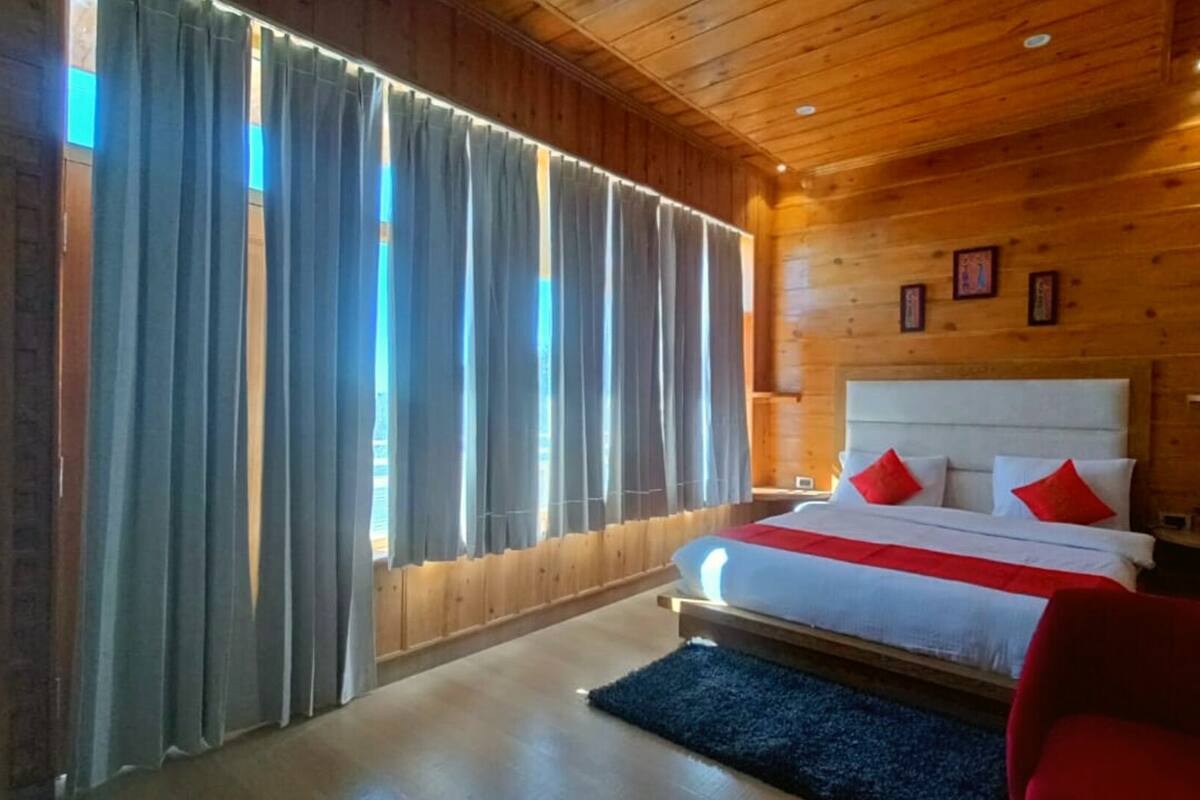 A wooden cabin bedroom with a bed, curtains, and a red chair.