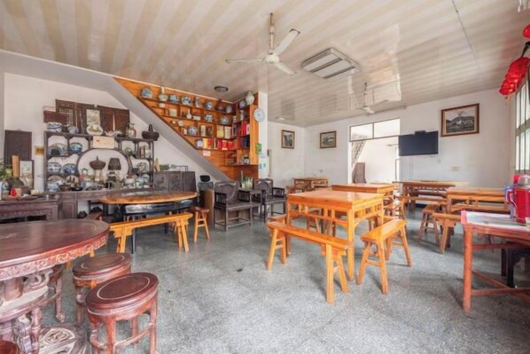 Una habitación con una escalera, varias mesas, sillas y una variedad de objetos en estanterías.