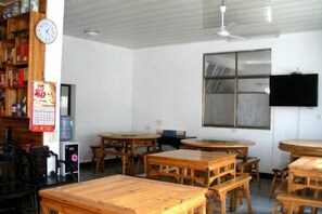 A room with multiple wooden tables and chairs, a clock on the wall, and a television mounted on the wall. - Qingyuan Farm Stay (Wuyuan)