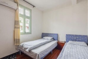 A small, clean room with two single beds, a window with green shutters, and a wooden floor. - Qingyuan Farm Stay (Wuyuan)