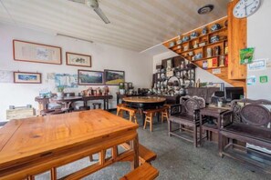 Una stanza con un tavolo da pranzo in legno, sedie, una scala con mensole e diverse immagini incorniciate alle pareti.