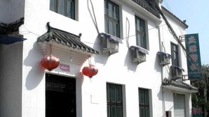 Un edificio tradicional con fachada blanca, varias ventanas y unidades de aire acondicionado.