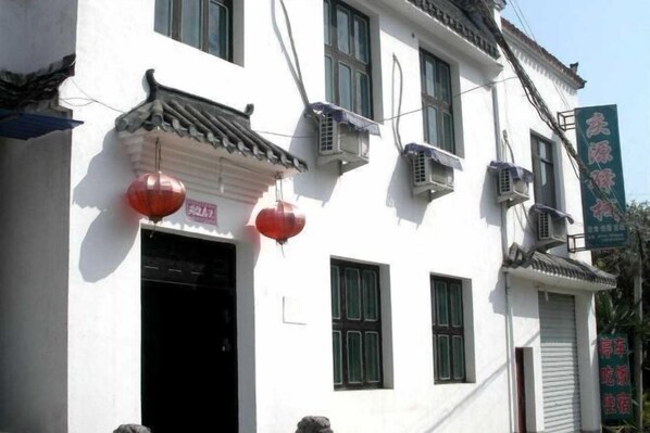 A traditional building with a white facade, multiple windows, and air conditioning units. - Qingyuan Farm Stay (Wuyuan)