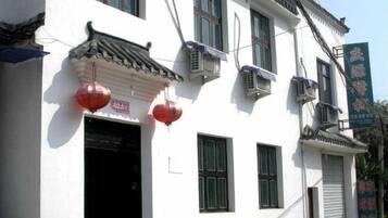 A traditional building with a tiled roof, air conditioning units, and a signboard.
