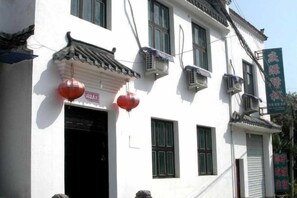 Un edificio tradizionale con tetto in tegole, condizionatori d'aria e una targa.