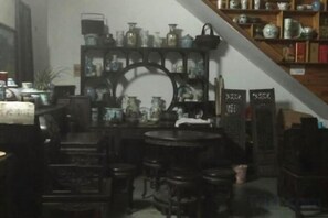 A room with a round table, chairs, and shelves with various items. - Qingyuan Farm Stay (Wuyuan)