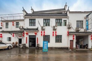 A traditional building with multiple windows and a tiled roof, featuring a blue signboard in front. - Qingyuan Farm Stay (Wuyuan)