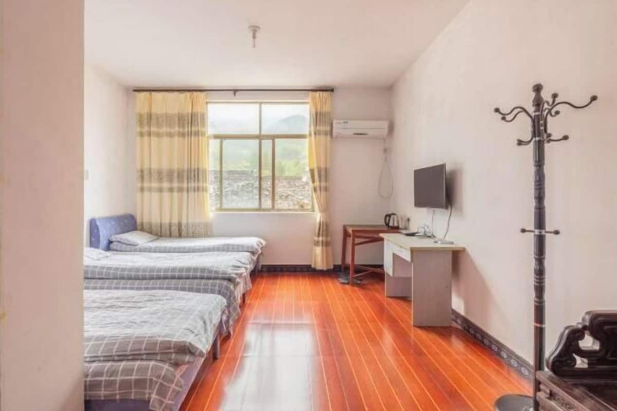 A room with two beds, a desk, a television, and a coat rack.