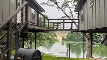 Enjoy a serene lakeside retreat with a balcony overlooking the water, a grassy lawn, and outdoor cooking facilities.