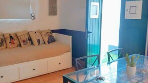 A room with a white sofa, a glass table, and a blue door. - Agroturismo Herdade Fonte Ferreira (Avis)