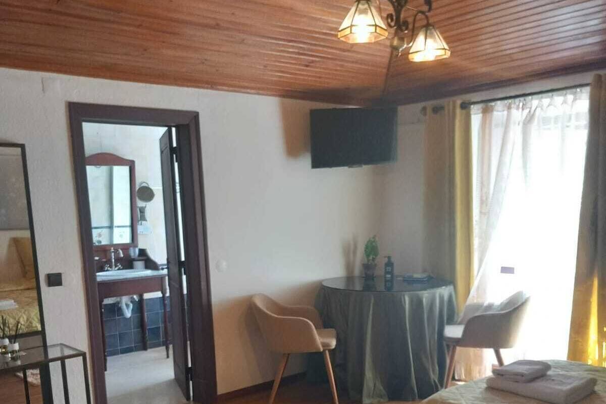 A bedroom with a bed, a desk, a chair, a television, and a bathroom visible through an open door.