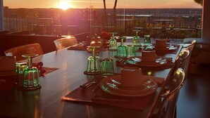 A dining table set for six with a view of the sunset over a cityscape. - Agroturismo Herdade Fonte Ferreira (Avis)