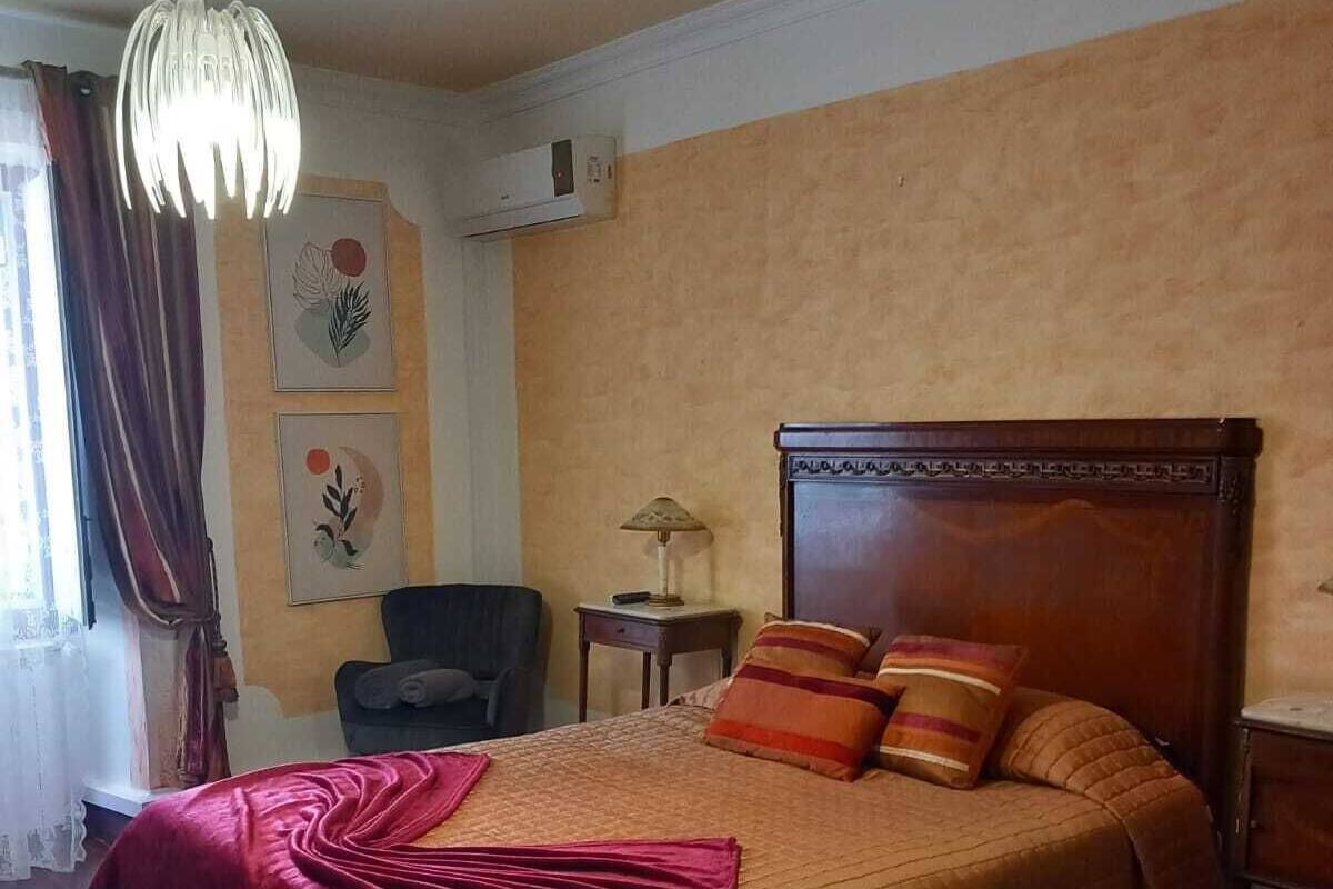 A bedroom with a large bed, a bedside table, a lamp, and a chair.