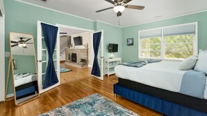 A bedroom with a bed, a ceiling fan, a window, and a view of the outside.