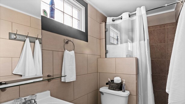 A bathroom with a white sink, a toilet, a glass shelf with towels, and a shower curtain. - Wilmington Beach Bungalow~ Kure Beach, Fishing, Pool, Walk to Pier (Kure Beach)