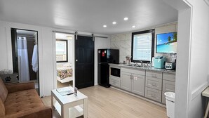 A modern apartment with a living room, kitchenette, and a bathroom. - Wilmington Beach Bungalow~ Kure Beach, Fishing, Pool, Walk to Pier (Kure Beach)