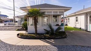 A single-story house with a covered porch, a palm tree, and a small garden area.