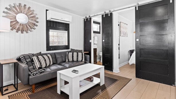 A modern living room with a grey sofa, white coffee table, and a large mirror.