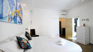 Une chambre d’hôtel moderne  équipée d’un grand lit, d’une chaise, d’une commode et d’un appareil de climatisation.