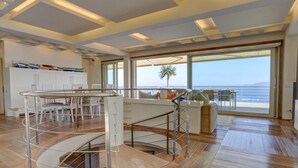 Ein großzügiger Wohnbereich mit einer runden Sitzecke, großen Fenstern mit Meerblick und einem modernen Interieur.