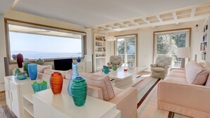 Ein modernes Wohnzimmer mit großem Fenster, einem weißen Sofa, einem Couchtisch mit dekorativen Vasen und einem Bücherregal.