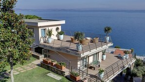 Ein modernes, zweistöckiges Haus mit Dachterrasse und Meerblick.