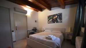 A bedroom with a bed, a desk, a chair, a painting, and a door. - Vista sui sassi civico 16 (Matera)