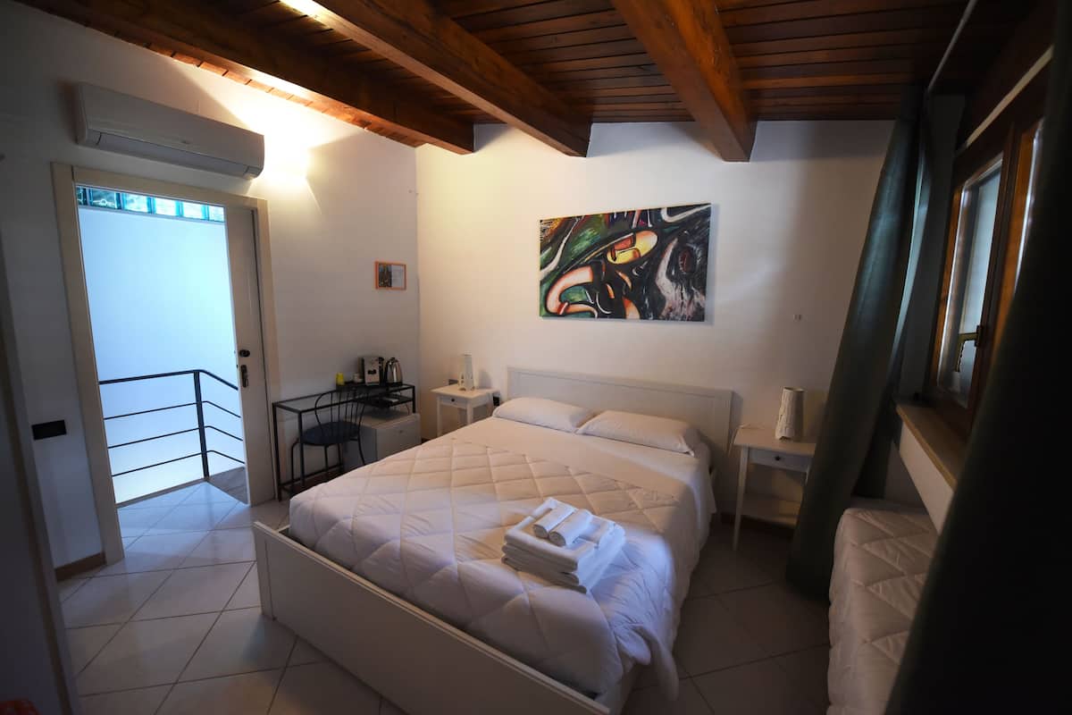 Quarto com cama grande, escrivaninha, cadeira, mesa de cabeceira e um quadro na parede.