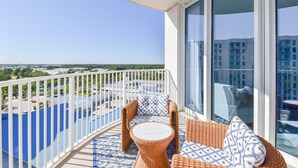 A balcony with wicker furniture, a view of the city, and a clear sky.