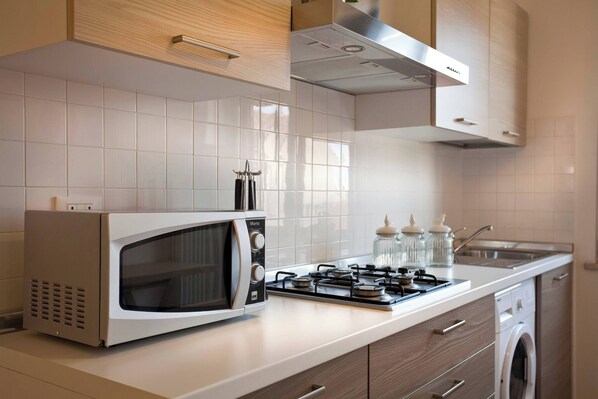 A modern kitchen with a built-in microwave, gas stove, and a washing machine.