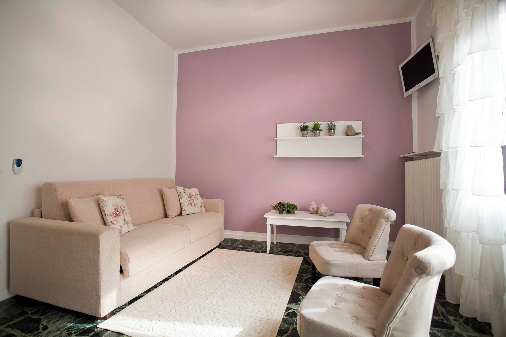 A living room with a sofa, armchair, small table, and decorative items on a wall.
